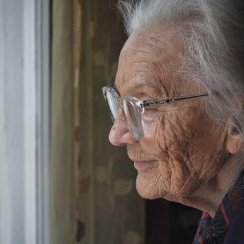 older person looking out window